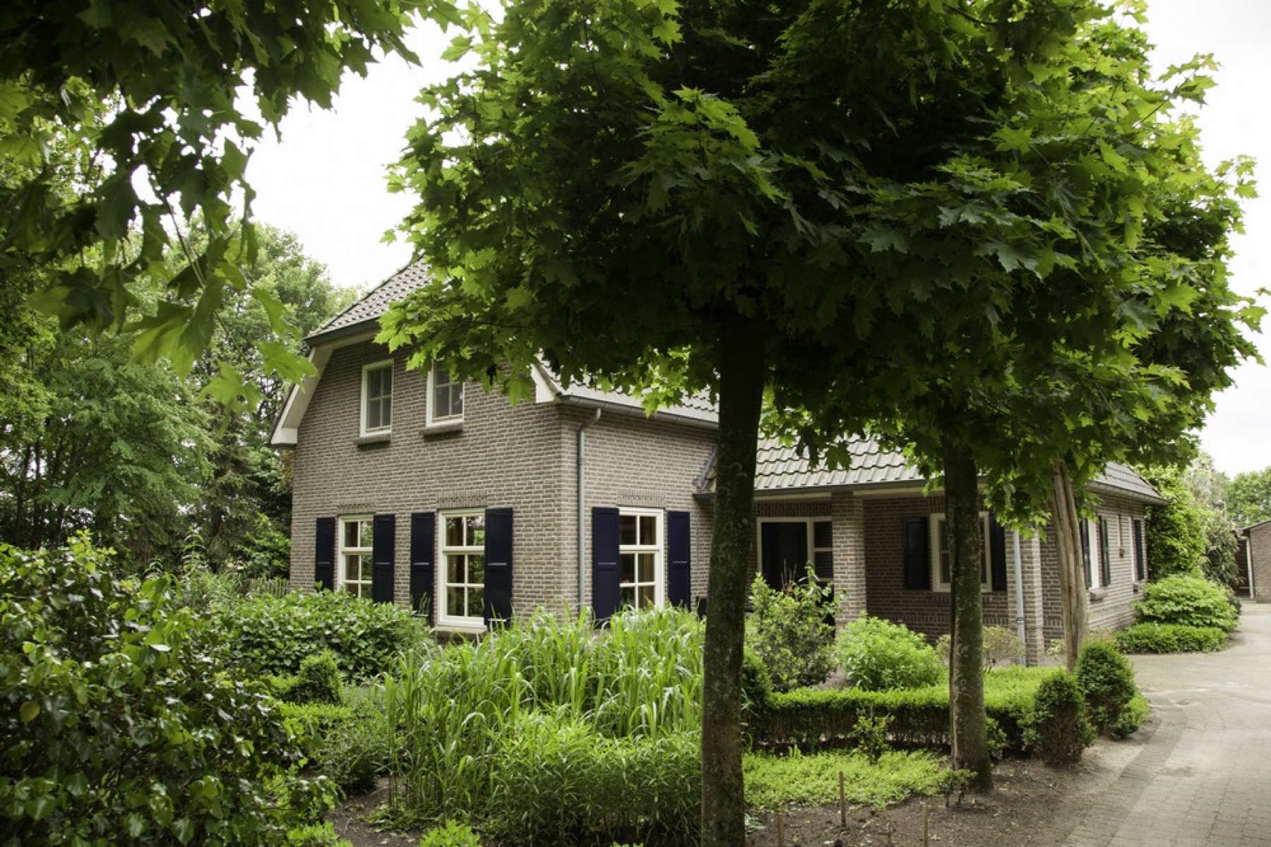 Het woonhuis van Zorgboerderij 't Spiek aan de Spiekweg, met bomen en een groene voortuin